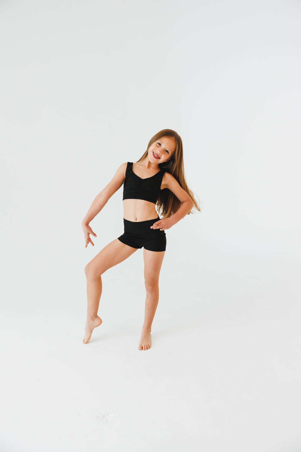 Young girl in black athletic wear posing on a white background