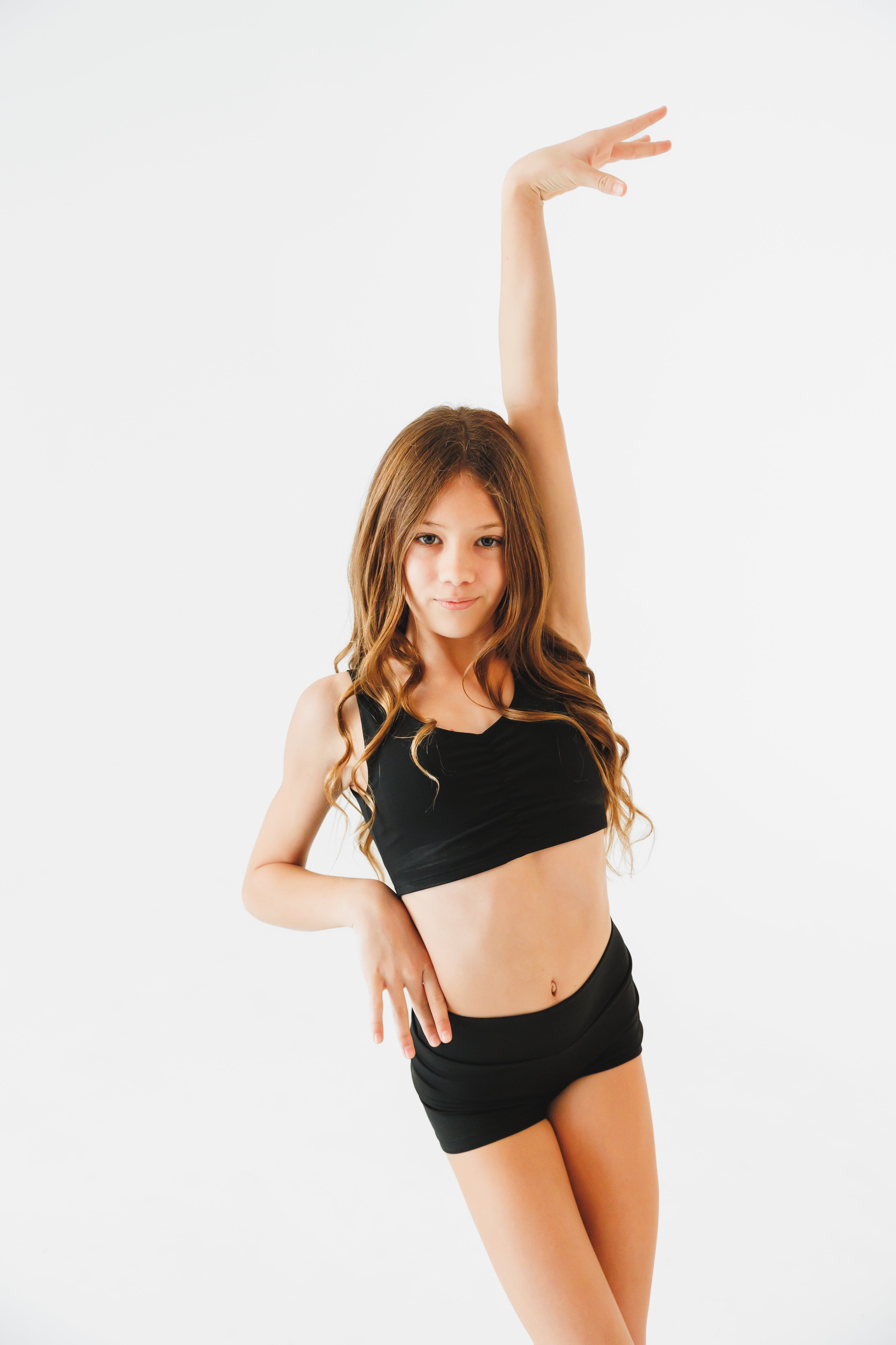girl in black athletic wear posing against a white background
