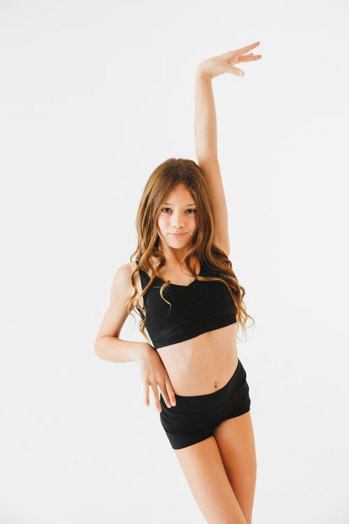 girl in black athletic wear posing against a white background