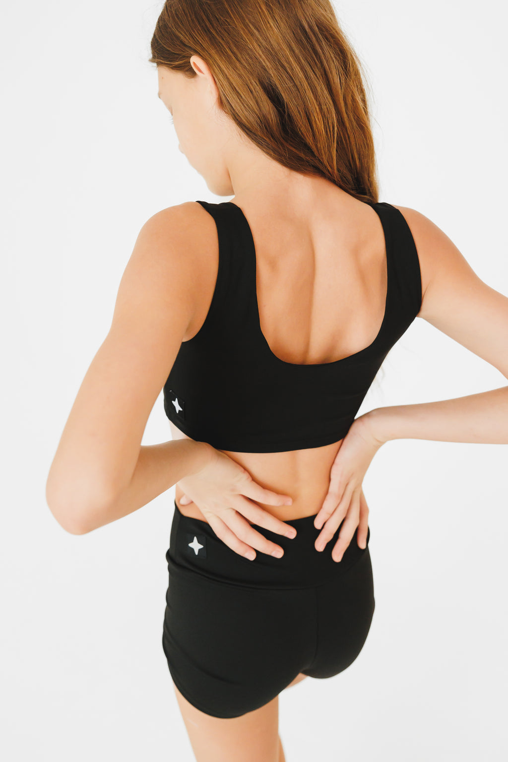 Woman wearing a black sports bra and shorts on a white background